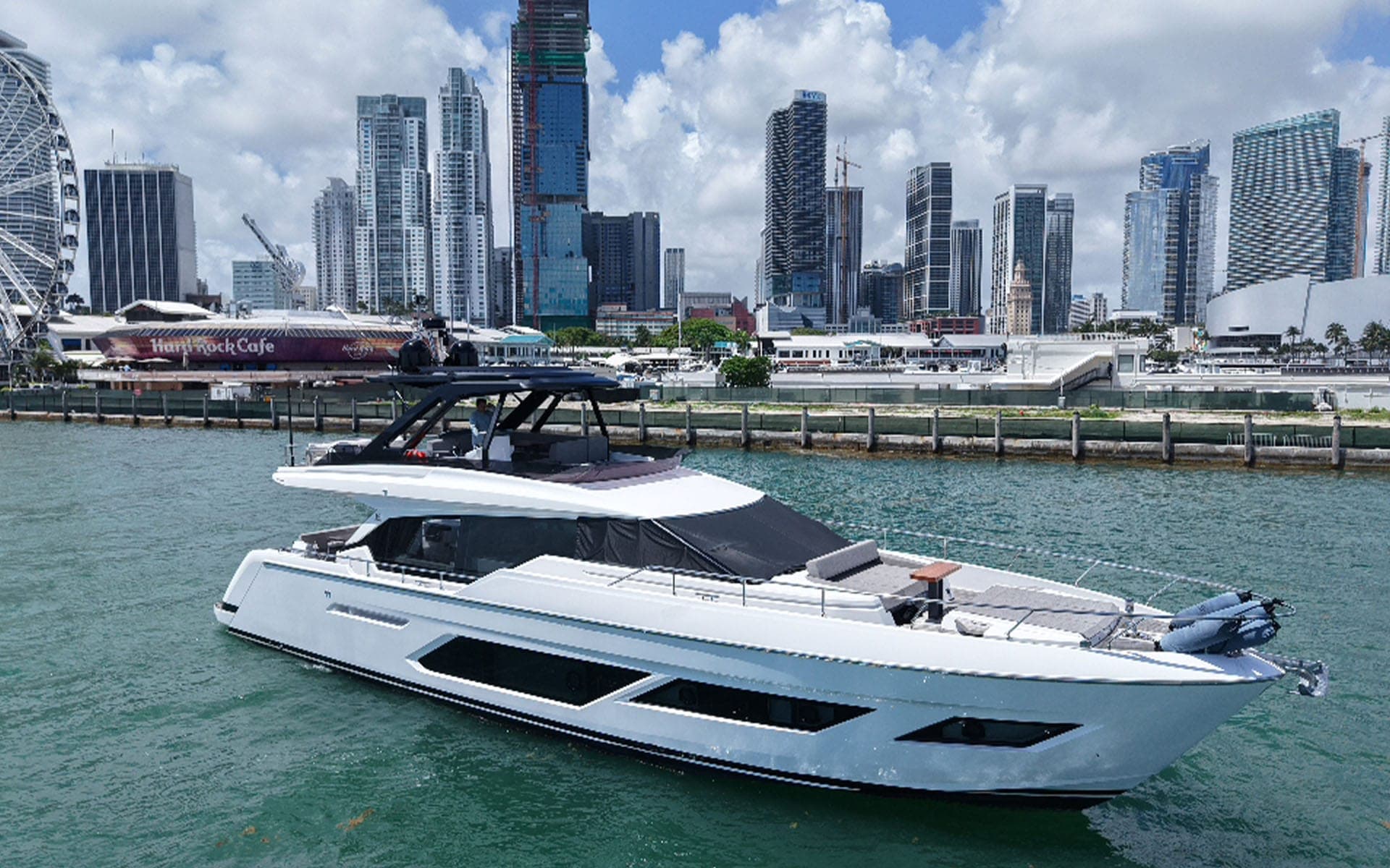 The 80' Ferretti on the Miami River with the downtown skyline behind, Well Played Editions charter yacht in Miami